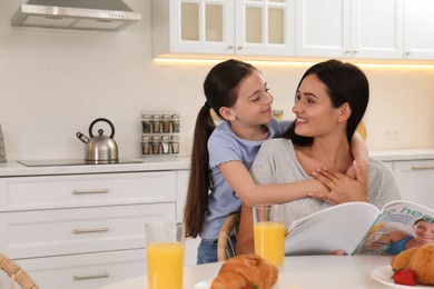 Little girl hugging her mother in kitchen. Single parenting