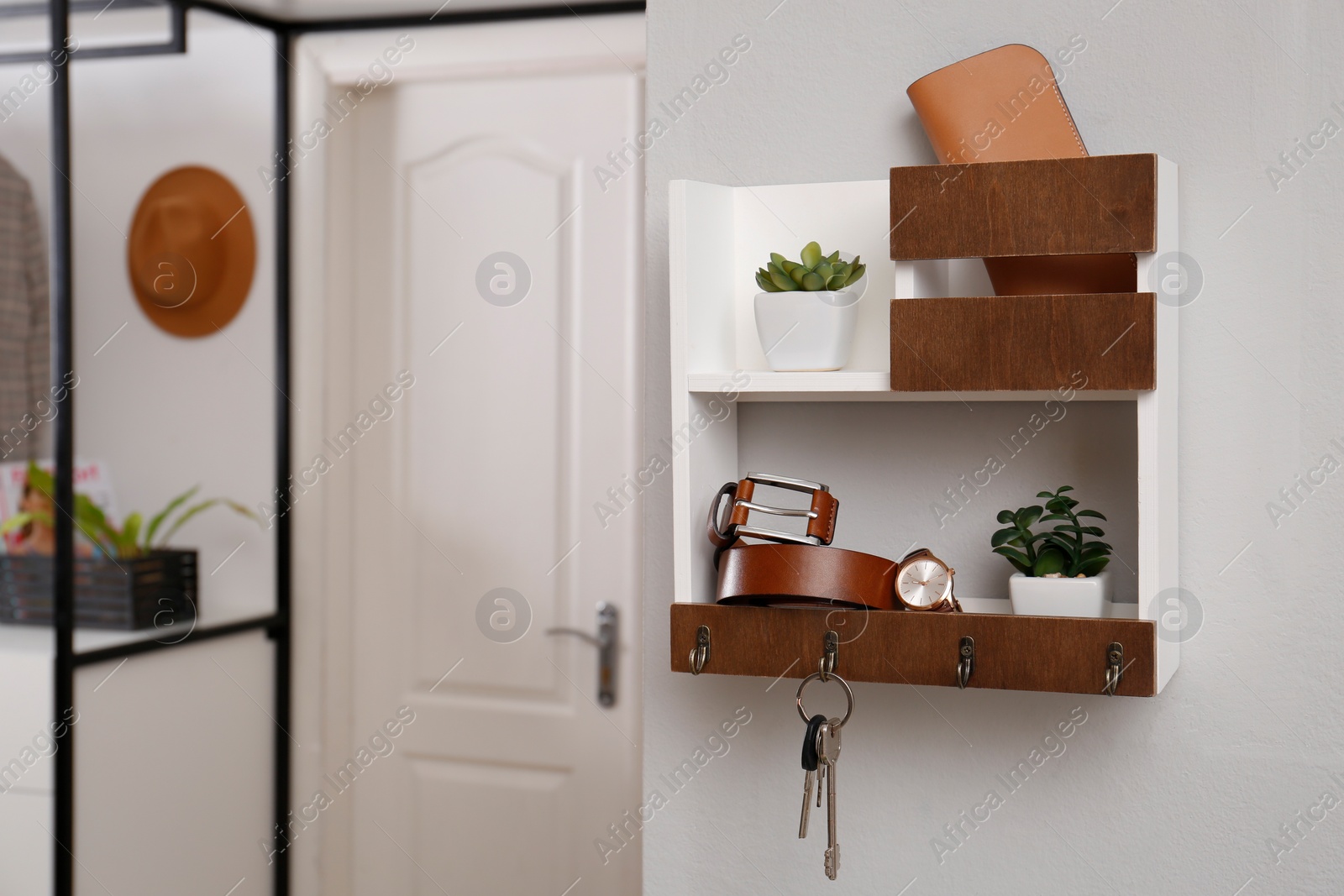 Photo of Hallway interior with stylish accessories and wooden hanger for keys on white wall