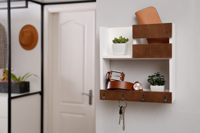 Hallway interior with stylish accessories and wooden hanger for keys on white wall