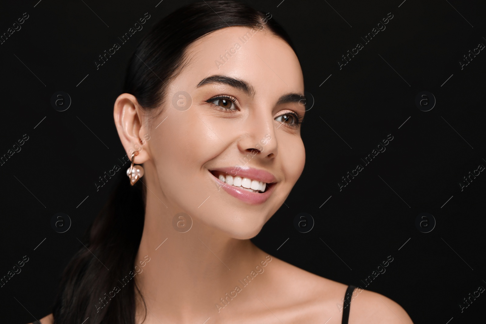 Photo of Young woman with elegant pearl earrings on black background, space for text