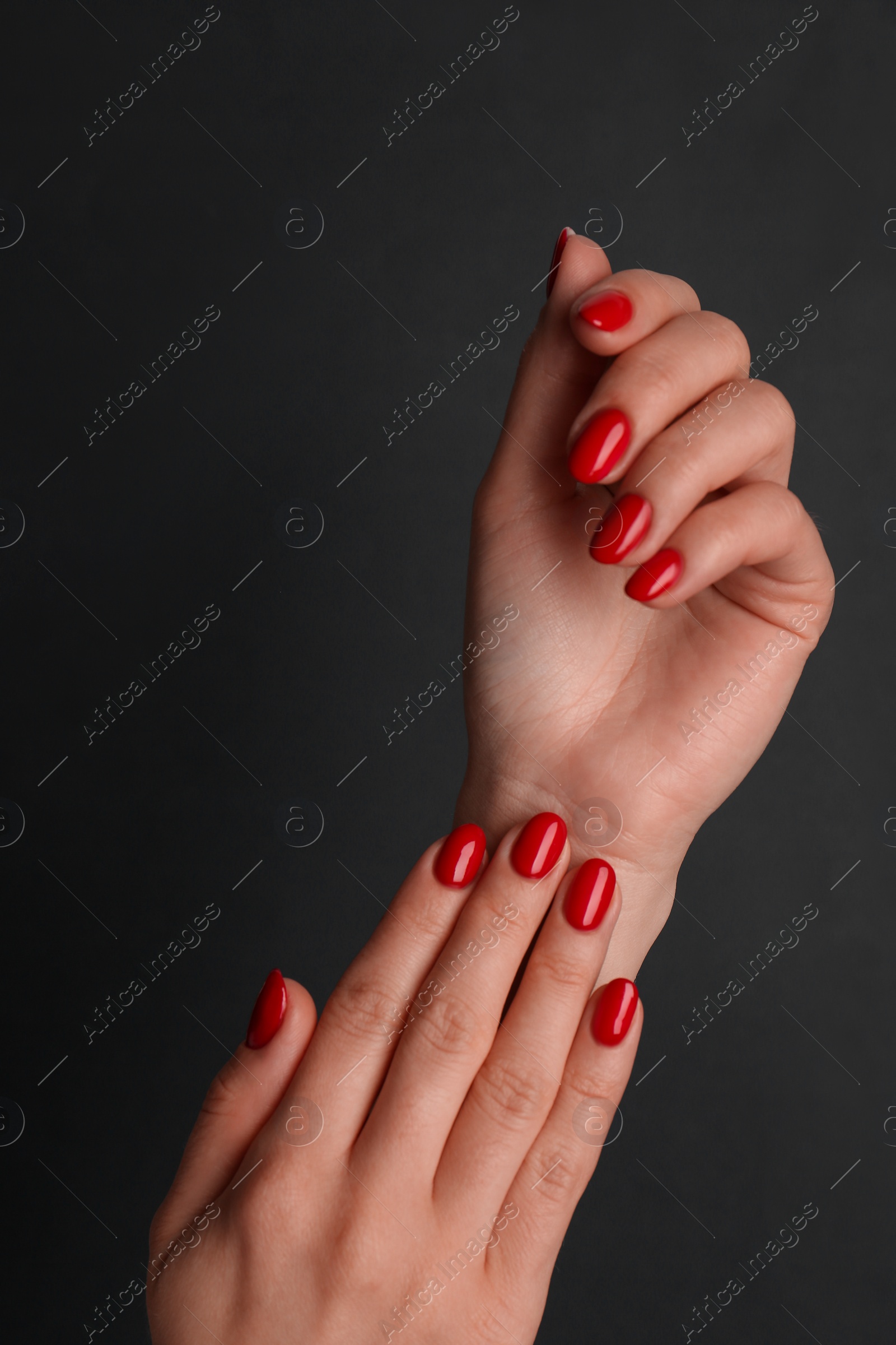 Photo of Woman with red polish on nails against black background, closeup