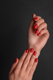 Photo of Woman with red polish on nails against black background, closeup