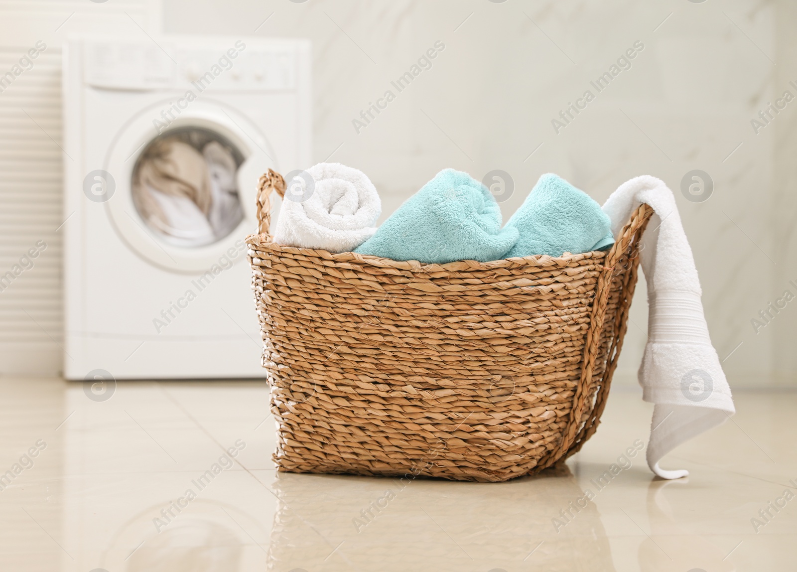 Photo of Wicker basket with fresh rolled towels in bathroom