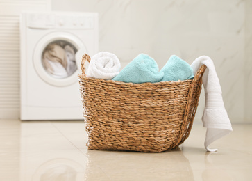 Photo of Wicker basket with fresh rolled towels in bathroom