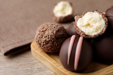 Photo of Many different delicious chocolate truffles on wooden table, closeup. Space for text