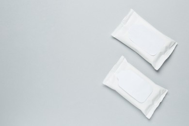 Wet wipes flow packs on light grey background, flat lay. Space for text