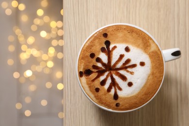 Cup of aromatic coffee on wooden table against blurred lights, top view. Space for text