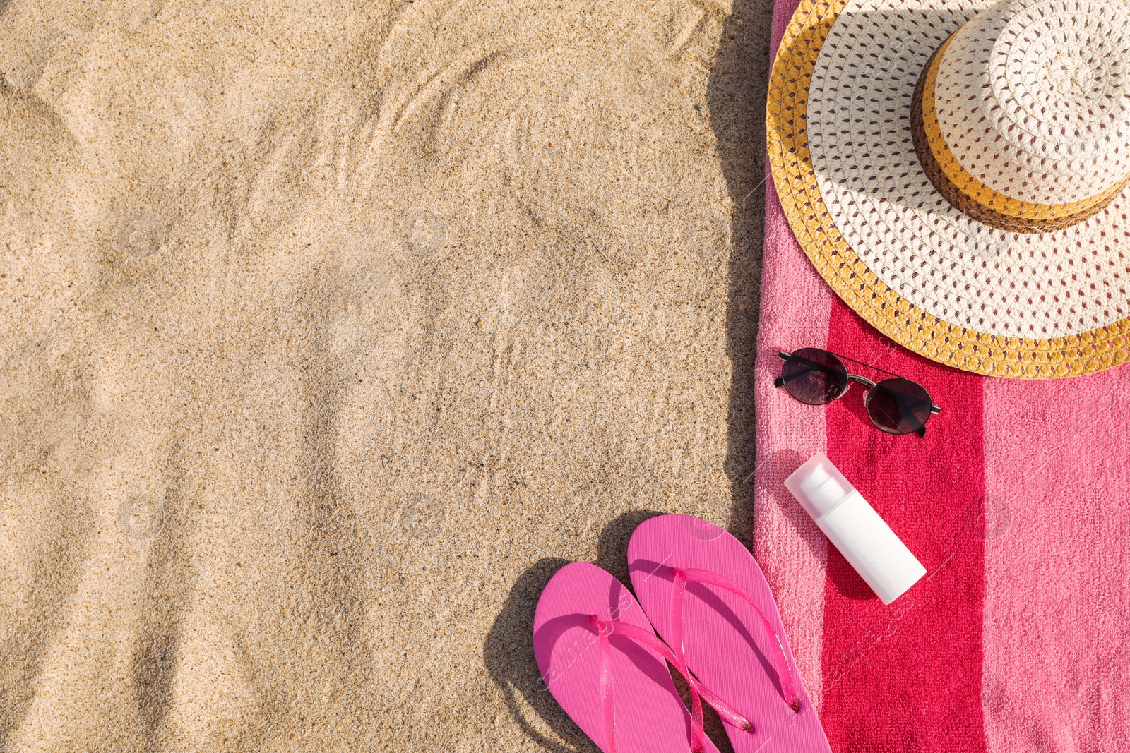 Photo of Towel and beach accessories on sand, flat lay. Space for text