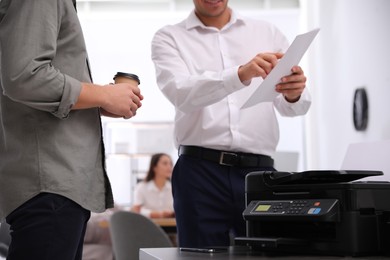 Photo of Employees near modern printer in office, closeup