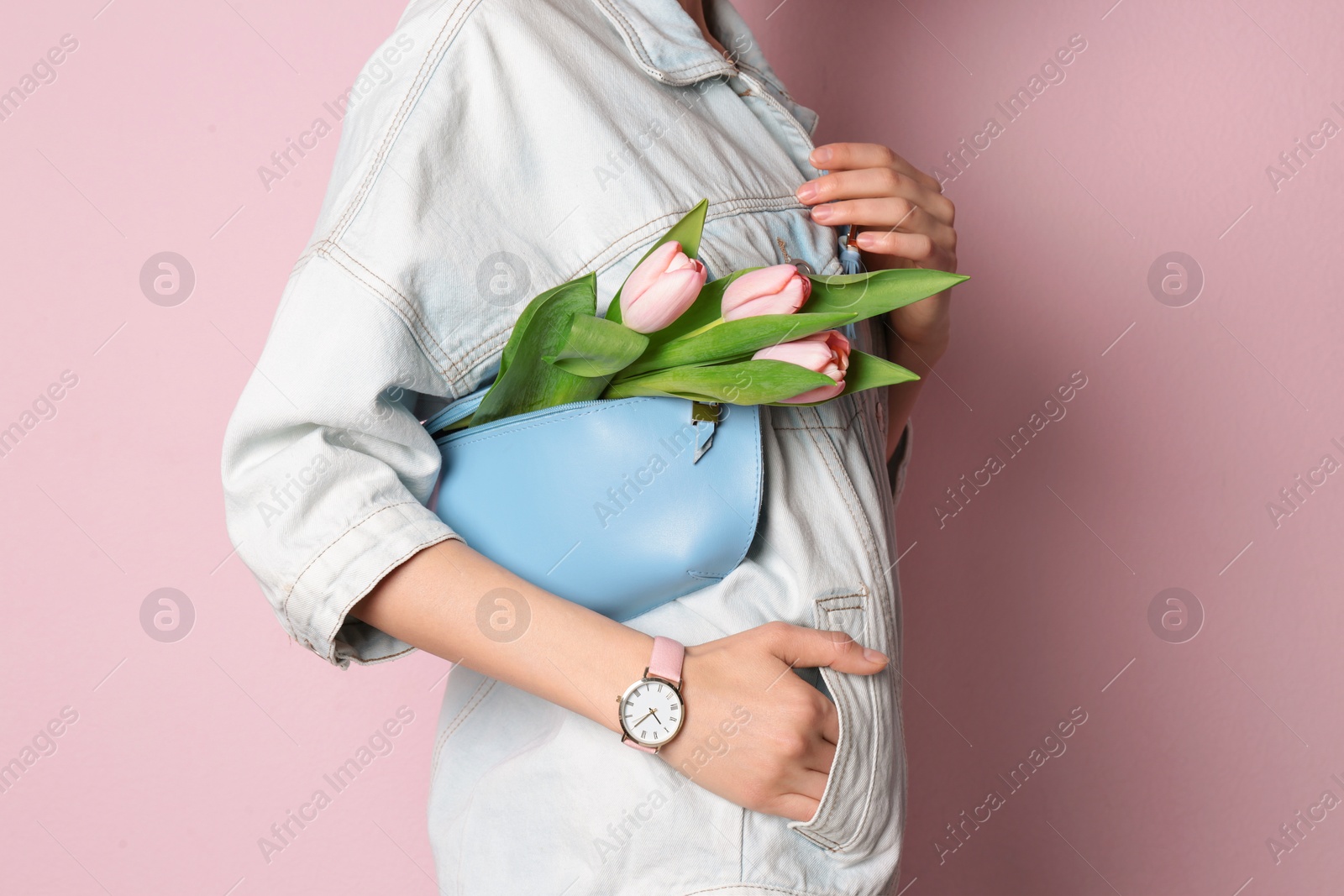 Photo of Stylish woman with bag and spring flowers against color background, closeup