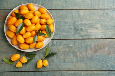 Photo of Fresh ripe kumquats on light blue wooden table, flat lay. Space for text