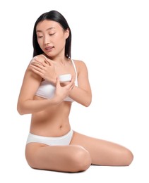 Beautiful young Asian woman applying body cream onto shoulder on white background