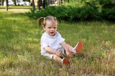 Little girl sitting on grass in park