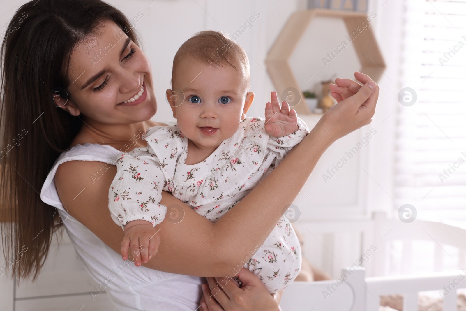 Photo of Happy young mother with her baby daughter in nursery