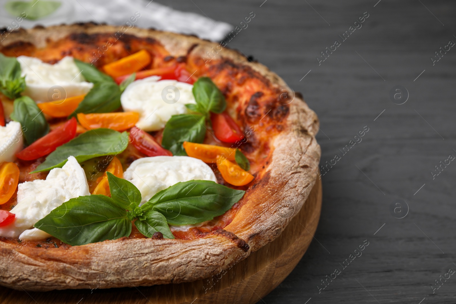 Photo of Delicious pizza with burrata cheese, tomatoes and basil on grey wooden table, closeup. Space for text