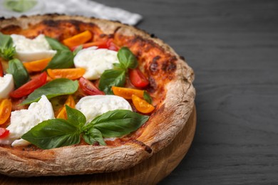 Photo of Delicious pizza with burrata cheese, tomatoes and basil on grey wooden table, closeup. Space for text