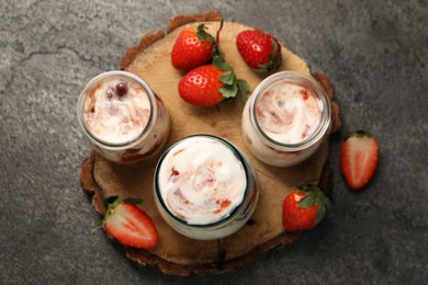 Tasty yoghurt with jam and strawberries on grey textured table, top view