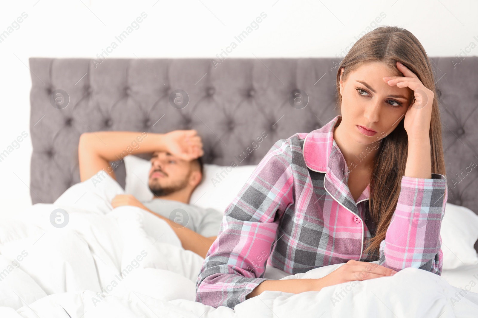 Photo of Young couple with relationship problems ignoring each other in bedroom