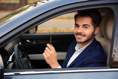 Photo of Young man holding car key in auto. Driving license test