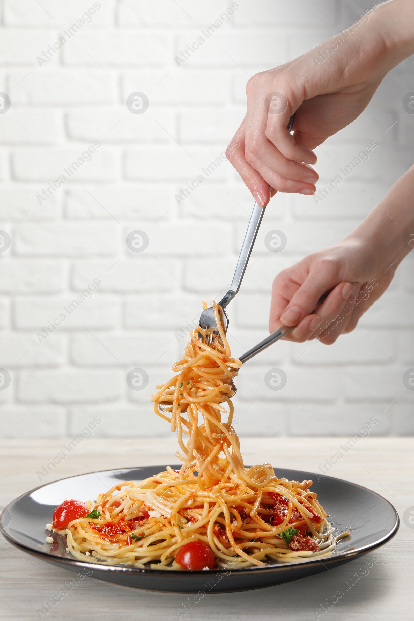 Photo of Woman eating delicious pasta at white wooden table, closeup