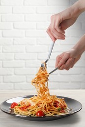 Woman eating delicious pasta at white wooden table, closeup