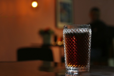 Photo of Glass of cola on table in dark room. Space for text
