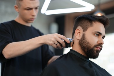 Professional hairdresser working with client in barbershop