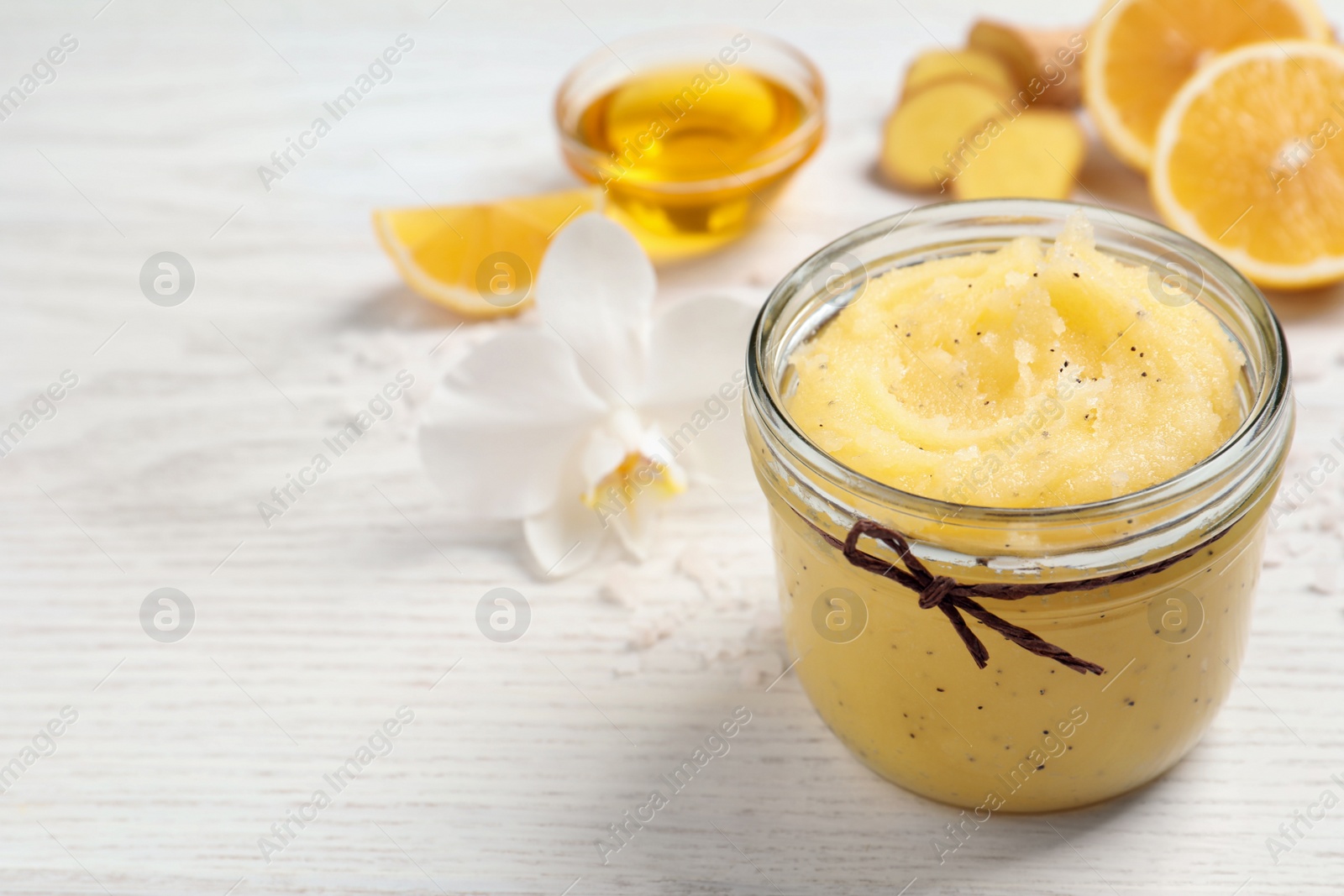 Photo of Body scrub in glass jar on white wooden table, closeup. Space for text