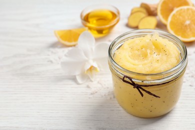 Body scrub in glass jar on white wooden table, closeup. Space for text