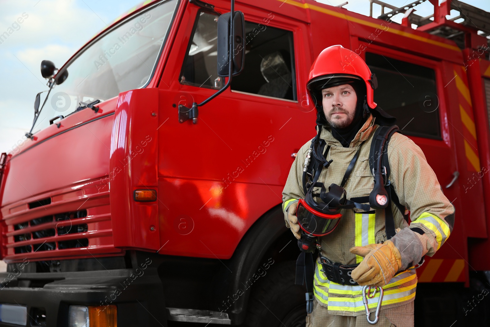 Photo of Firefighter in uniform near red fire truck at station