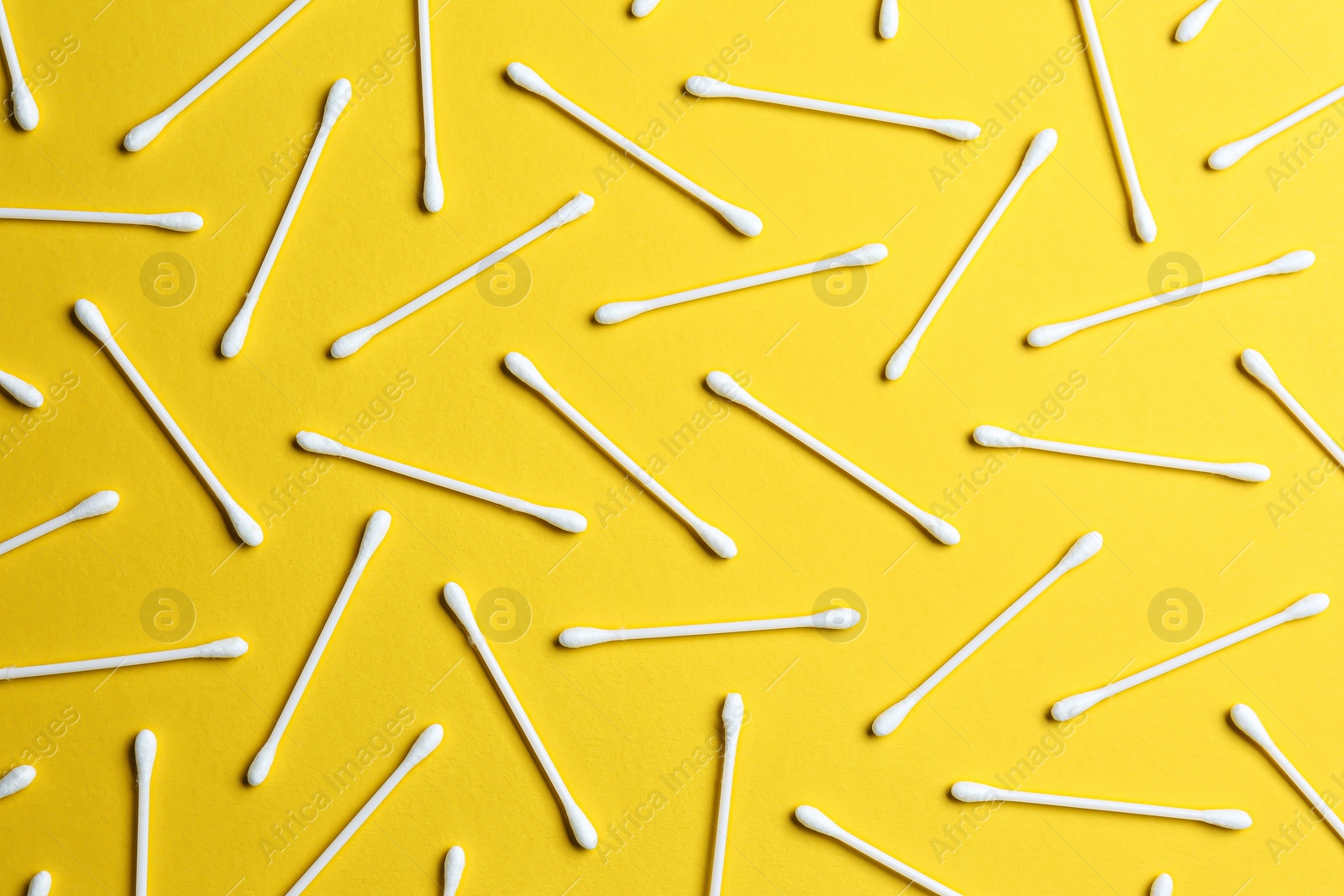 Photo of Many cotton buds on yellow background, flat lay