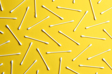 Many cotton buds on yellow background, flat lay