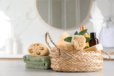 Natural loofah sponges, personal hygiene products and towel on table indoors