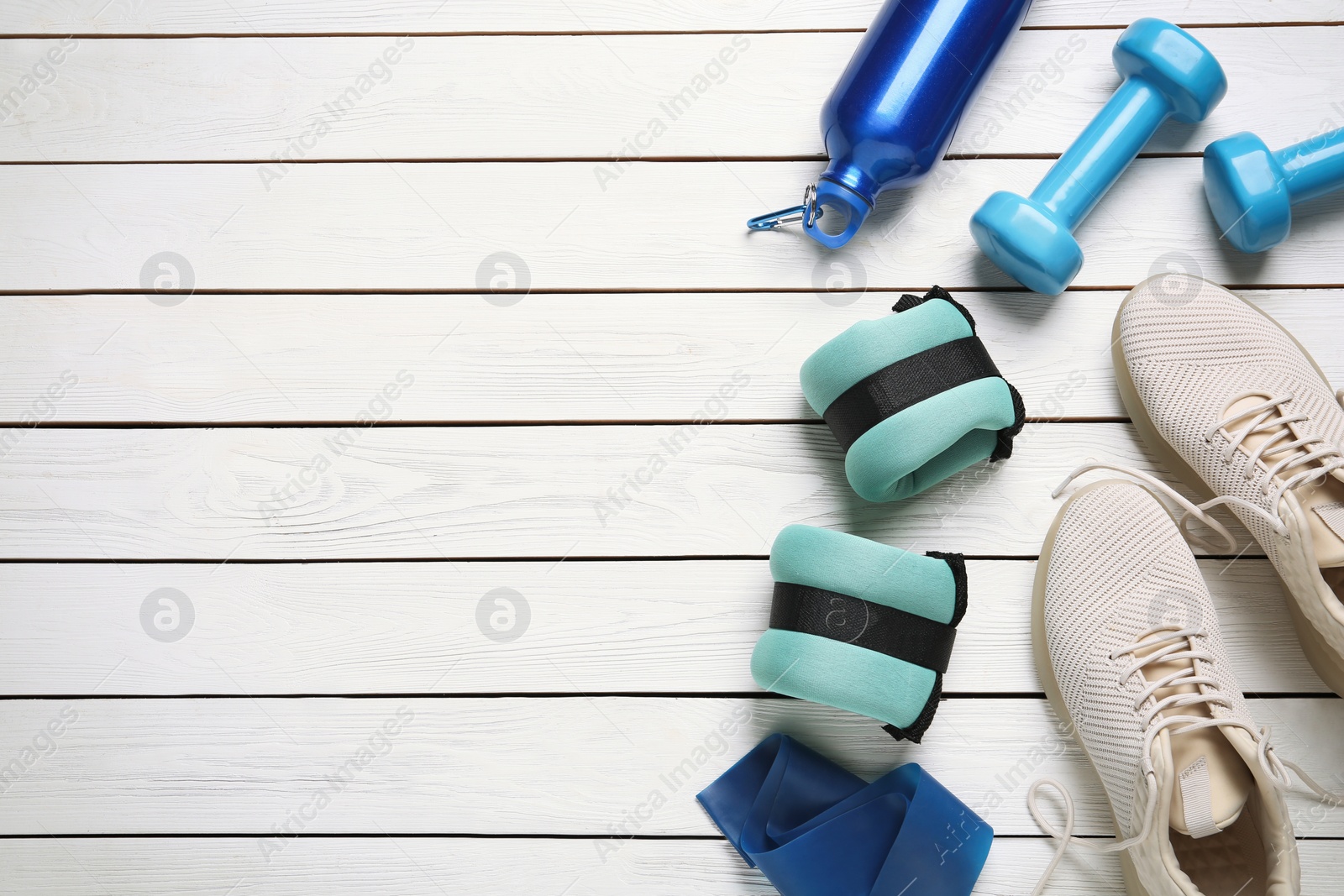 Photo of Turquoise weighting agents and sport equipment on white wooden table, flat lay. Space for text