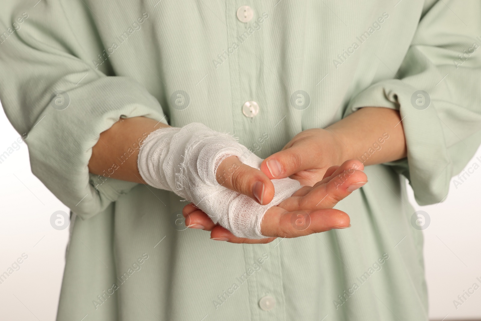 Photo of Woman with hand wrapped in medical bandage on white background, closeup