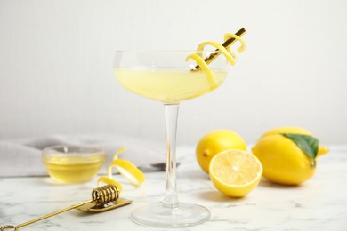 Photo of Delicious bee's knees cocktail and ingredients on white marble table
