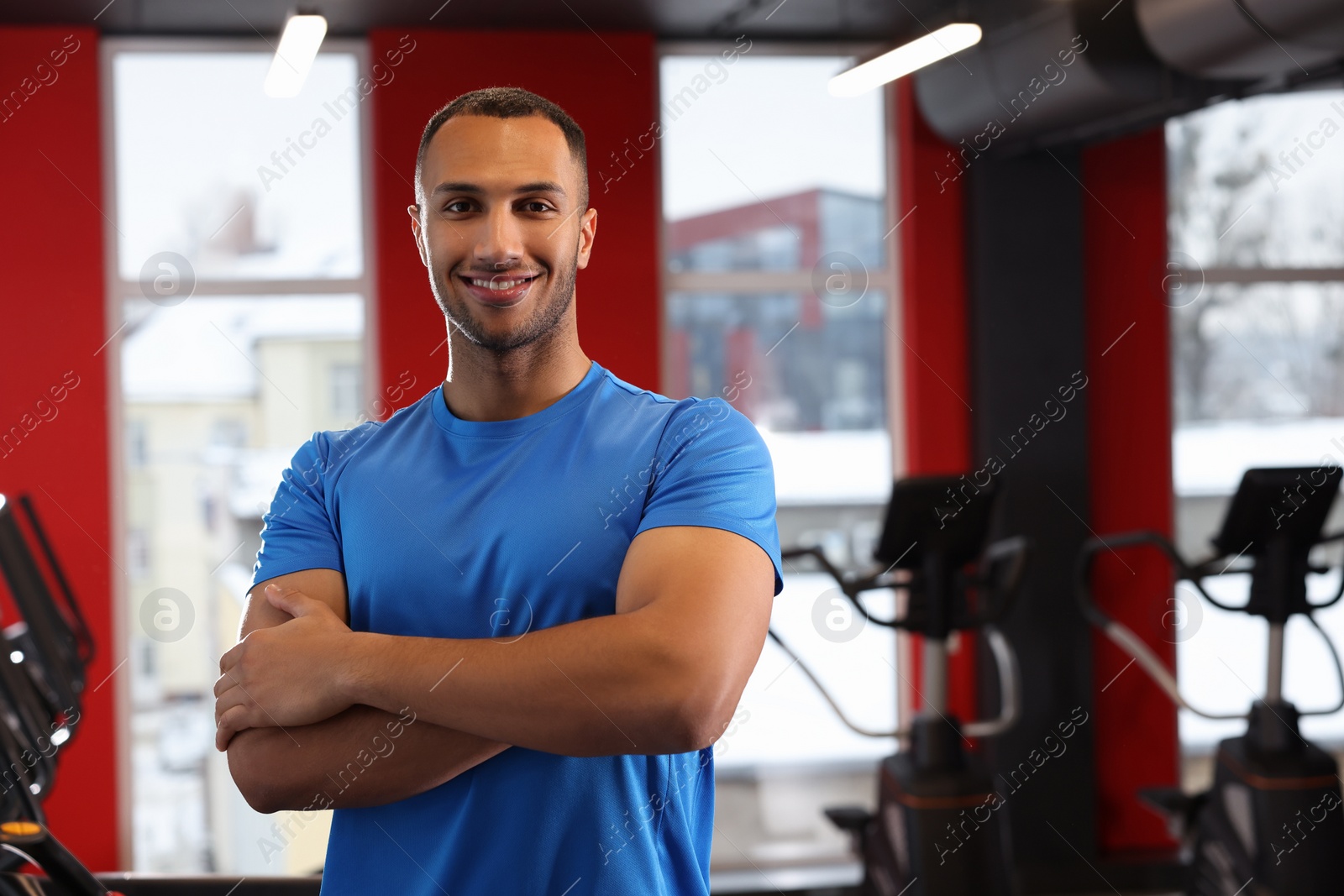 Photo of Happy trainer in modern gym, space for text