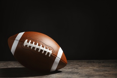 Photo of New American football ball on table against dark background