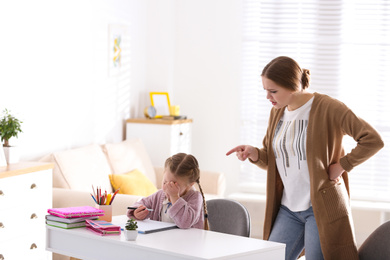 Mother scolding her daughter while helping with homework indoors