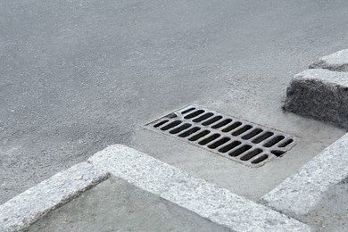 Photo of Metal drain grate on asphalt outdoors, space for text