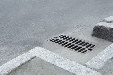 Metal drain grate on asphalt outdoors, space for text