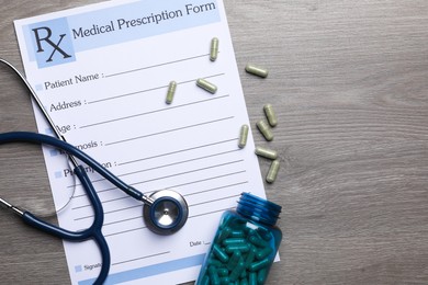 Photo of Medical prescription form, stethoscope and pills on wooden table, flat lay. Space for text