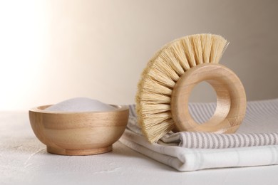 One cleaning brush, detergent and cloth on white textured table, closeup