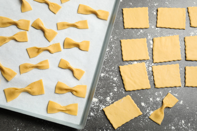 Photo of Homemade farfalle pasta on grey table, flat lay