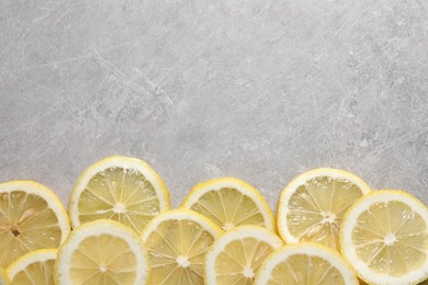 Photo of Slices of fresh lemons on grey table, top view. Space for text