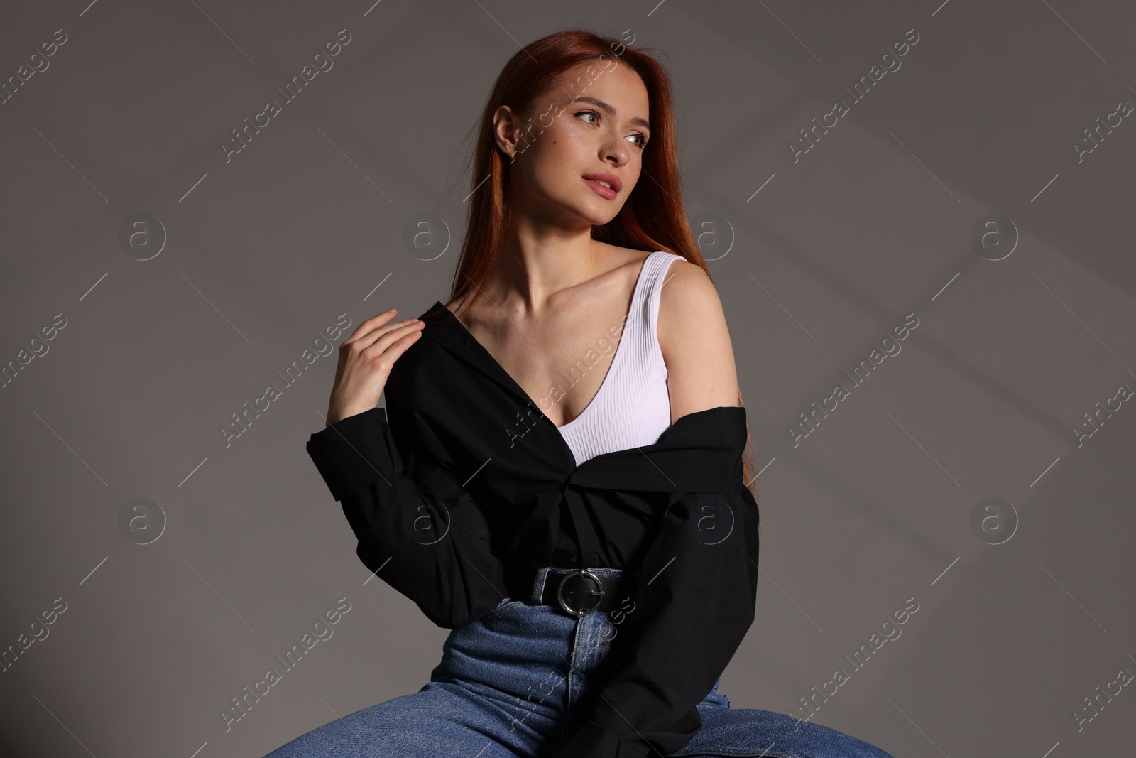 Photo of Beautiful young woman in black shirt on gray background