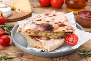 Photo of Tasty pizza calzones with cheese and different products on wooden table, closeup