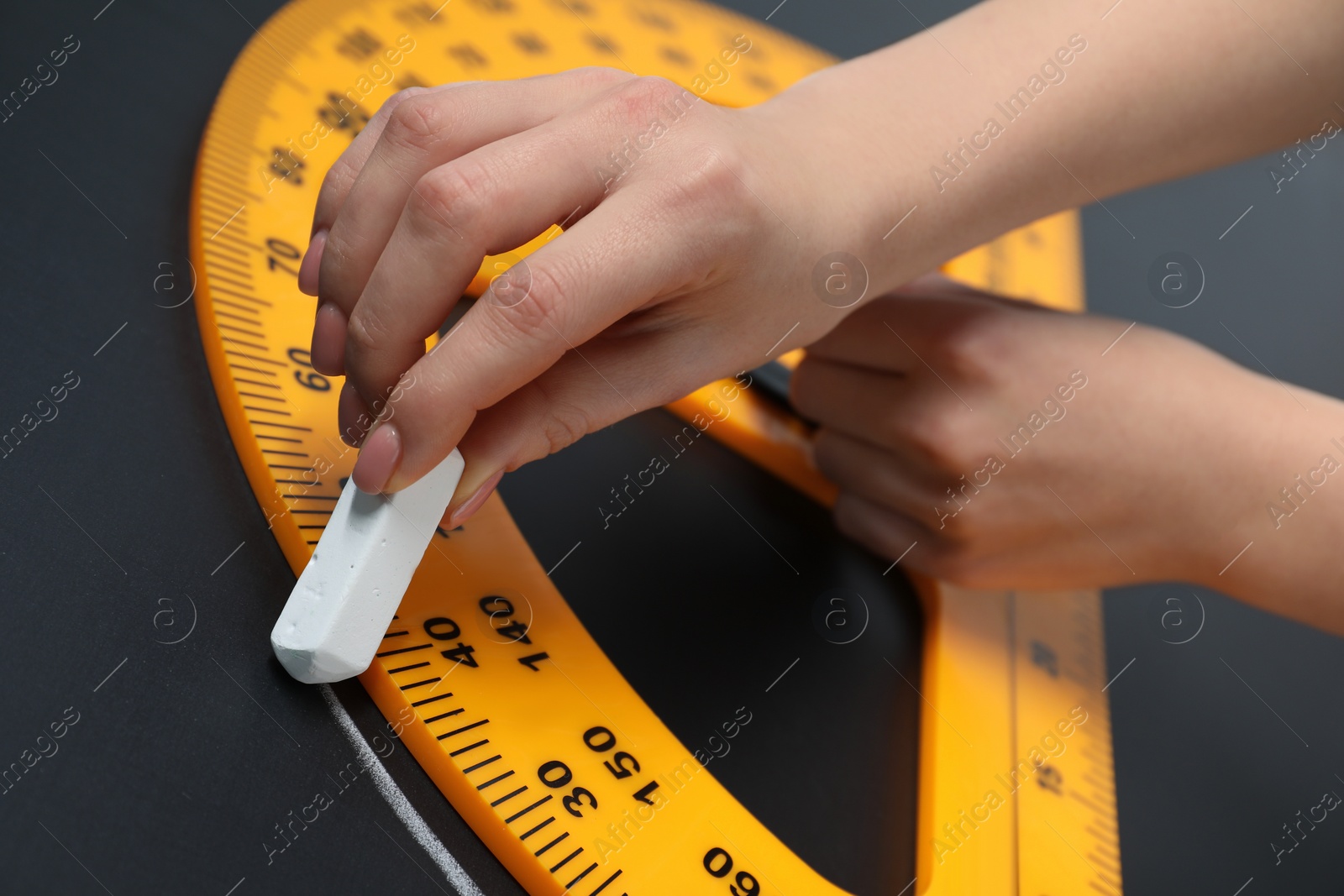 Photo of Woman drawing with chalk and protractor on blackboard, closeup