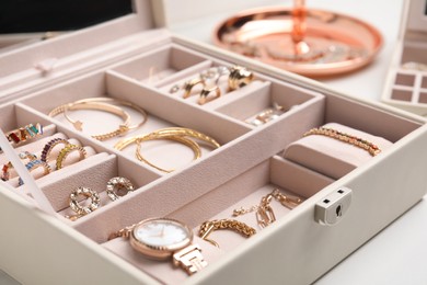 Photo of Jewelry box with stylish golden bijouterie on white table, closeup