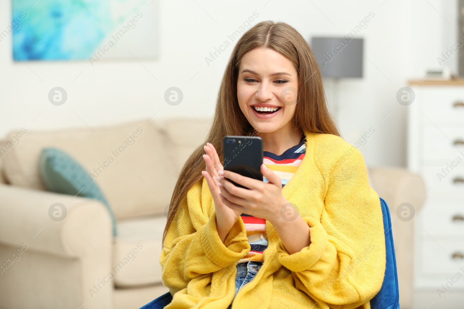 Photo of Happy young woman playing online lottery using smartphone at home